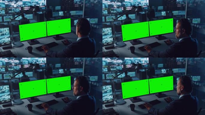 男警官在港口监视中心的一台带有两个绿屏模型的计算机上工作，该计算机的数字大屏幕上有多个摄像头。员工坐
