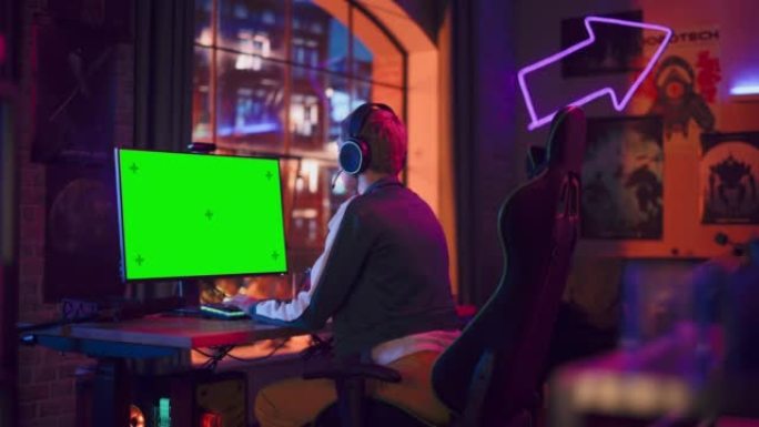 兴奋的女玩家玩在线视频游戏，在她强大的计算机上模拟绿屏。房间和电脑有彩色霓虹灯。阁楼公寓舒适的夜晚。