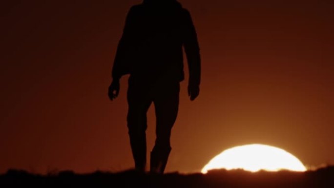 黄昏时在田野上行走的农民的SLO MO剪影。