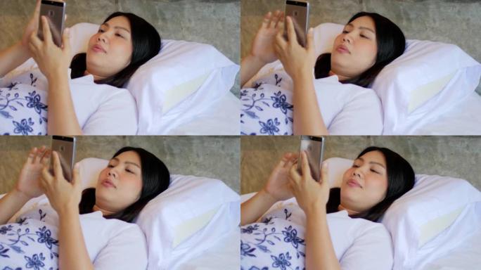 年轻女子在卧室的床上使用智能手机放松和触摸