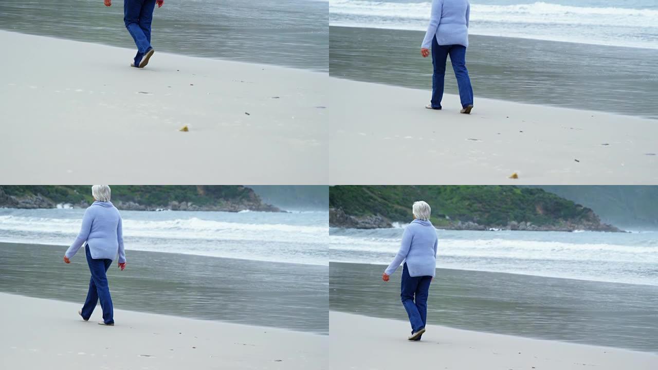 在海滩上散步的高级女性的后视图