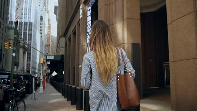 年轻的女商人走过美国纽约金融区到办公室的后景。慢动作