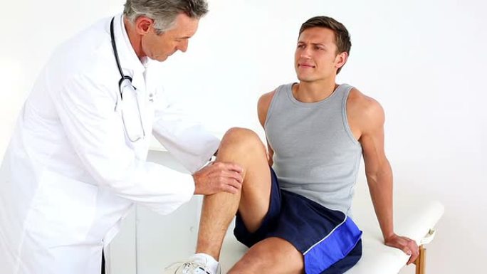 成熟的医生检查运动员受伤的膝盖