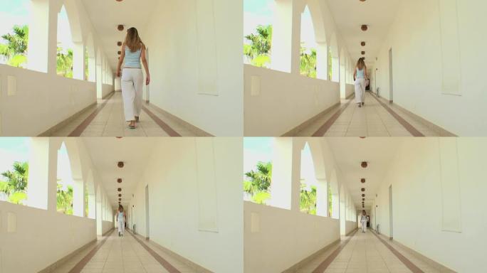 一名妇女穿过阿拉伯风格建筑的长走廊