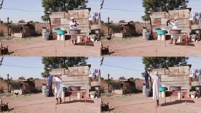 没有自来水的非洲妇女在锡棚屋前的水桶里洗衣服