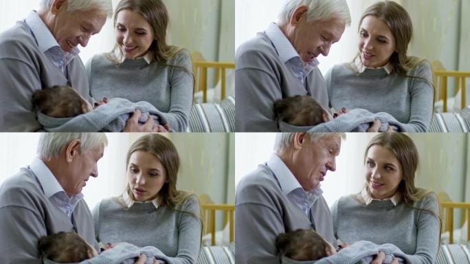 快乐的爷爷抱着熟睡的婴儿