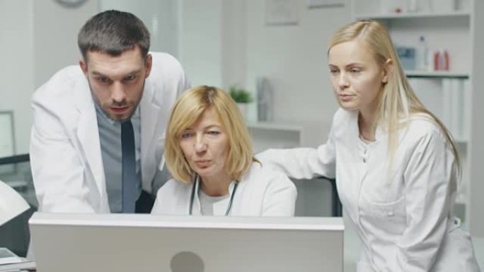 医务人员在使用个人计算机时讨论与工作相关的问题。男医生指着屏幕。他们点头同意。