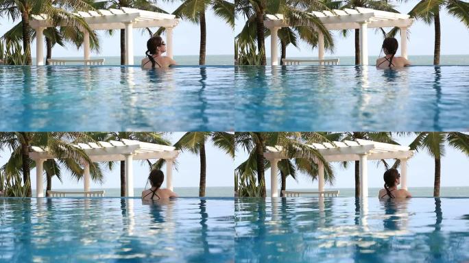 热带度假酒店的女子在无限泳池内放松