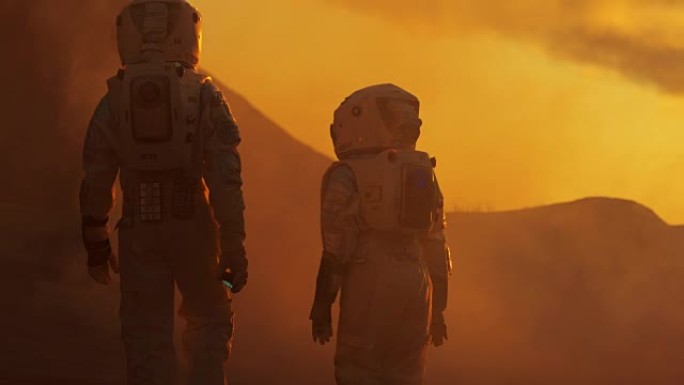 两名宇航员穿着宇航服漫步探索火星/红色星球的后视图。太空旅行，探索和殖民概念。