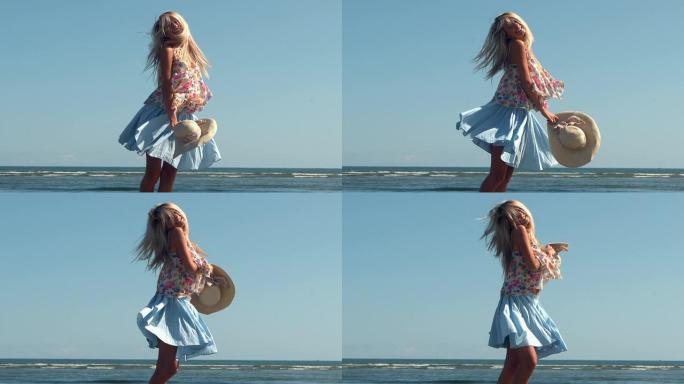 迷人的金发女郎拿着草帽在海滩上旋转