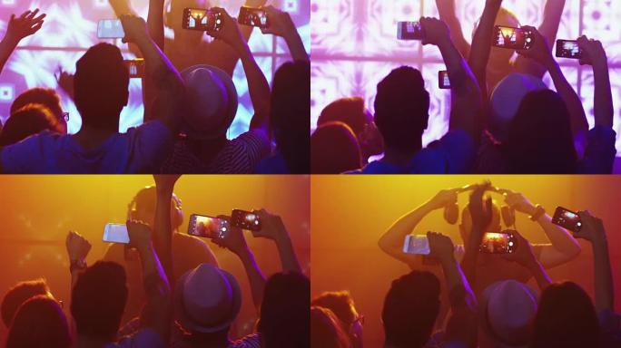 DJ在夜总会播放音乐，人们跳舞，用手机录制演唱会。