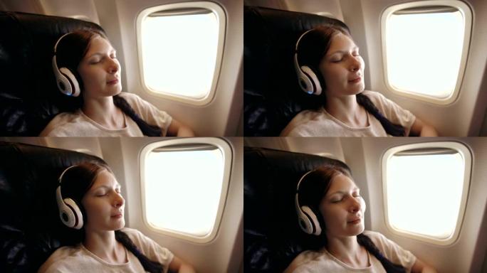 戴着无线耳机的年轻女子在飞机上听音乐和微笑