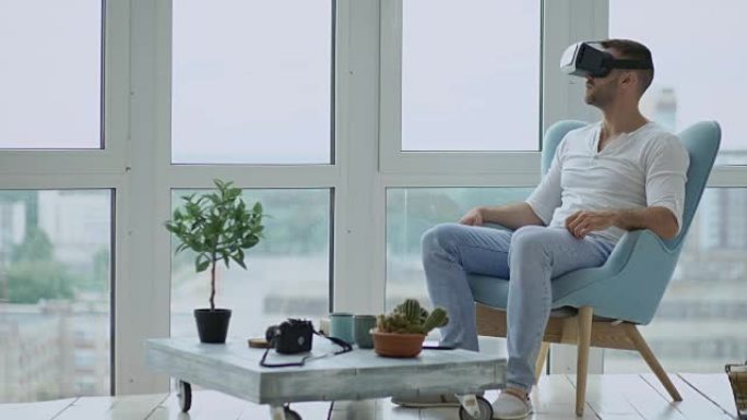 年轻人有使用虚拟现实耳机观看电影的VR体验坐在阳台的椅子上