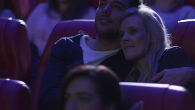 年轻幸福的浪漫夫妇正在电影院看电影放映。
