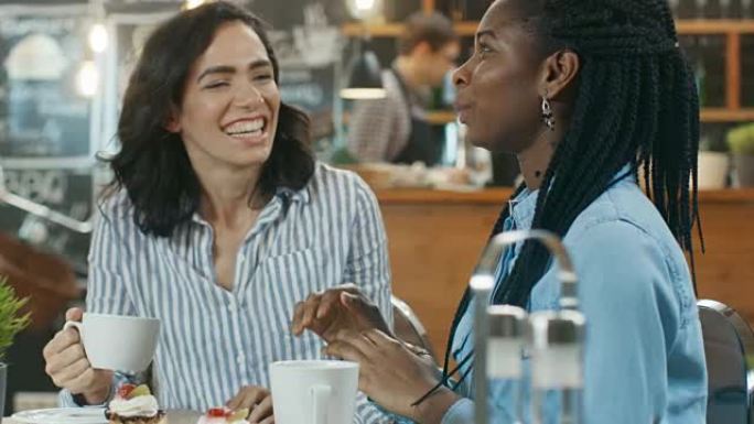 两个漂亮的女人坐在咖啡馆里，喝饮料吃甜点。他们一起聊天，玩得开心。背景是现代时尚的咖啡馆。