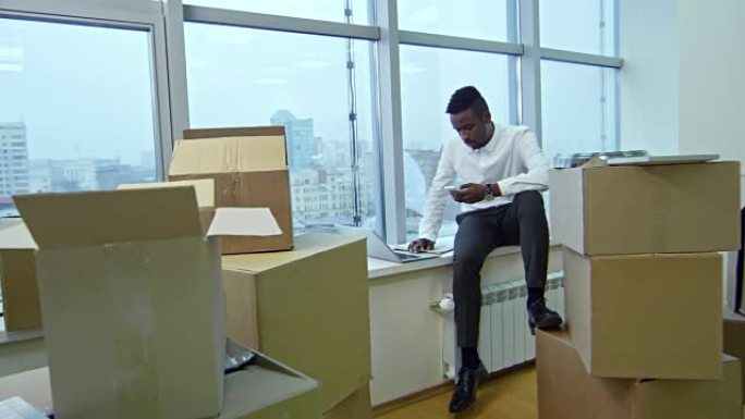 搬到新办公室后，在笔记本电脑上工作并使用电话的商人