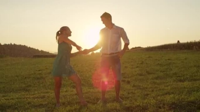 镜头耀斑: 可爱的赤脚男人和女人在迷人的日落时优雅地跳舞。