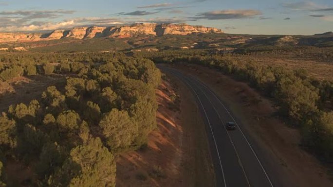 空中: 黑色SUV汽车驶向犹他州阳光明媚的梅萨山脉