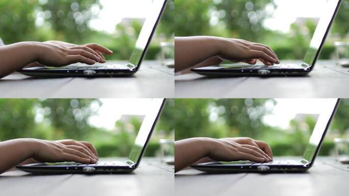 女人用手在绿色背景的笔记本电脑键盘上打字，在家工作