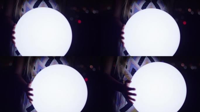 女人的手在晚上拿着发光的球灯