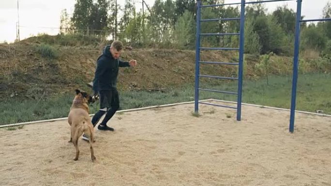 年轻的运动型男子在公园户外与他的斗牛犬一起训练，并为比赛做准备