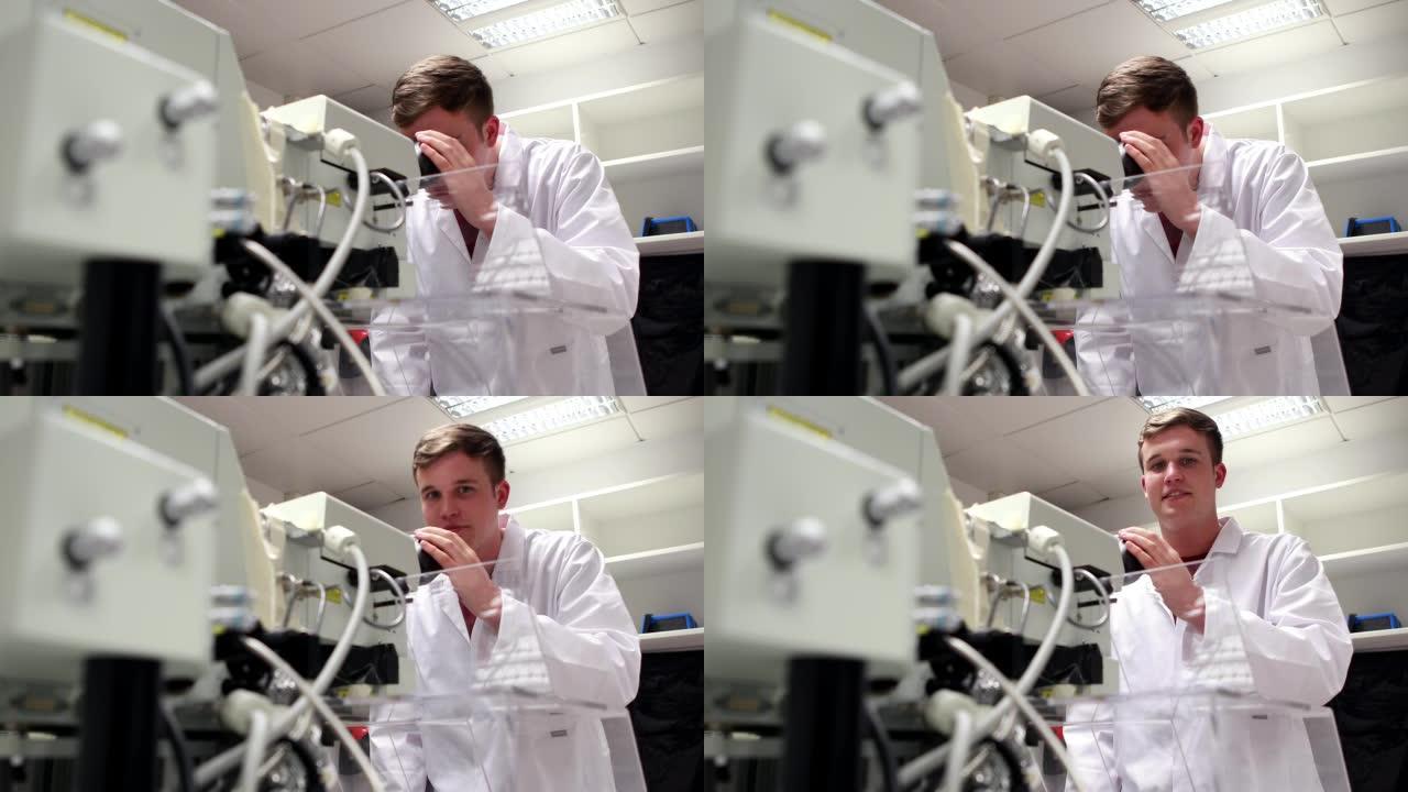年轻的理科学生通过高功率显微镜观察