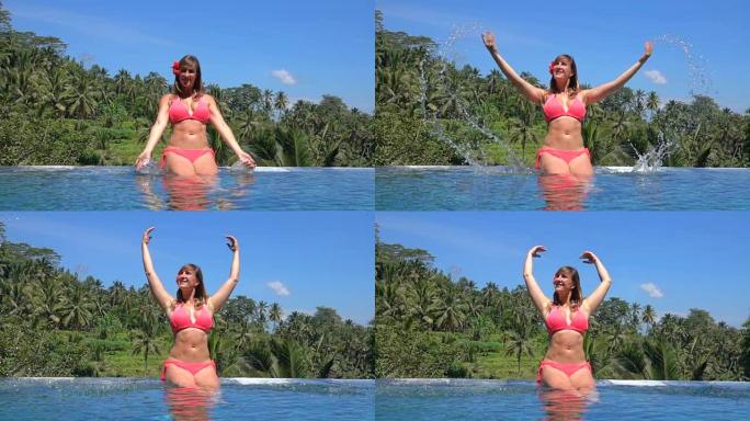 慢动作: 女孩在阳光明媚的天堂岛上的无边泳池里泼水