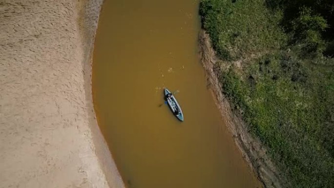 在小河转弯处享受皮划艇的游客。两个人划着船。俯视无人机4k。宁静的静修