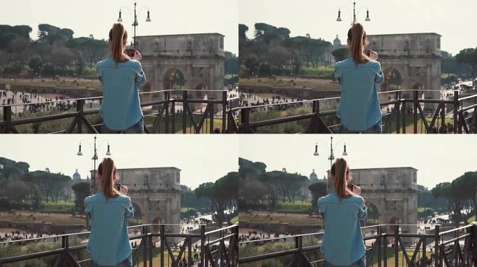 在阳光明媚的日子里，年轻女子在意大利罗马用智能手机拍摄君士坦丁拱门的照片。慢动作