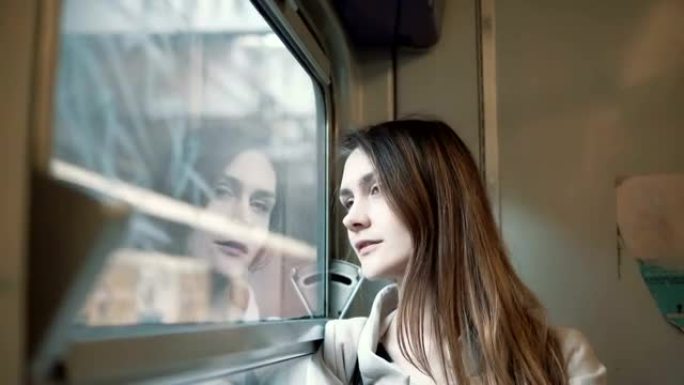 年轻漂亮的女人坐火车旅行。迷人的女孩看着窗户，探索外面的风景