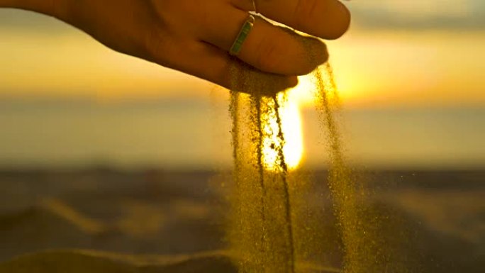 慢动作，反转: 日出时，粗粒沙粒从雌性手中掉落。