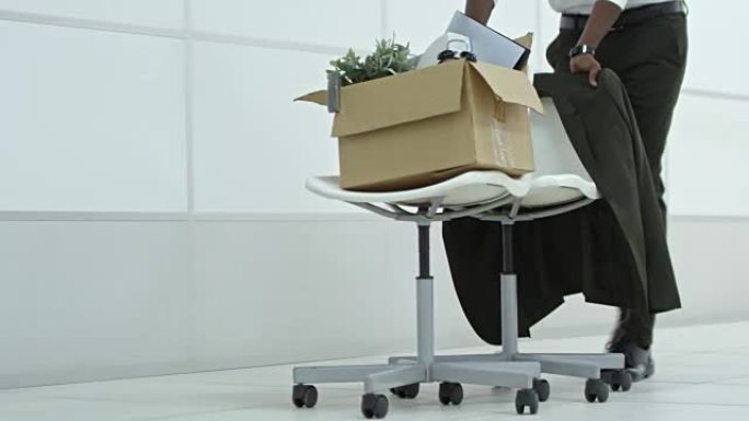 商人的腿将带有物品的办公椅推到新的工作场所