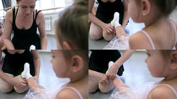 老师帮助女孩穿芭蕾舞鞋