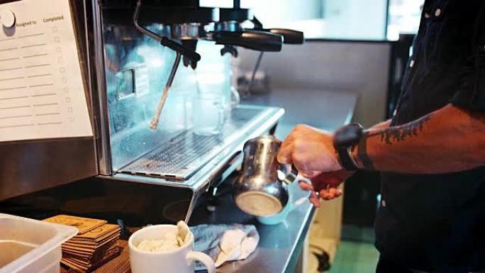 咖啡师将热牛奶添加到咖啡中的特写镜头