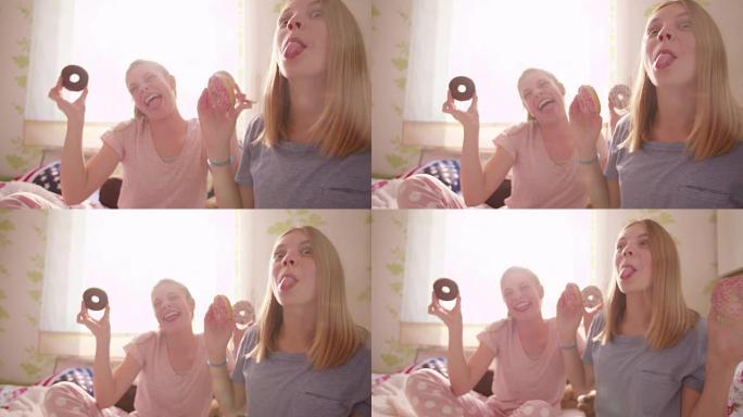 十几岁的女孩一起在卧室里笑着吃甜甜圈