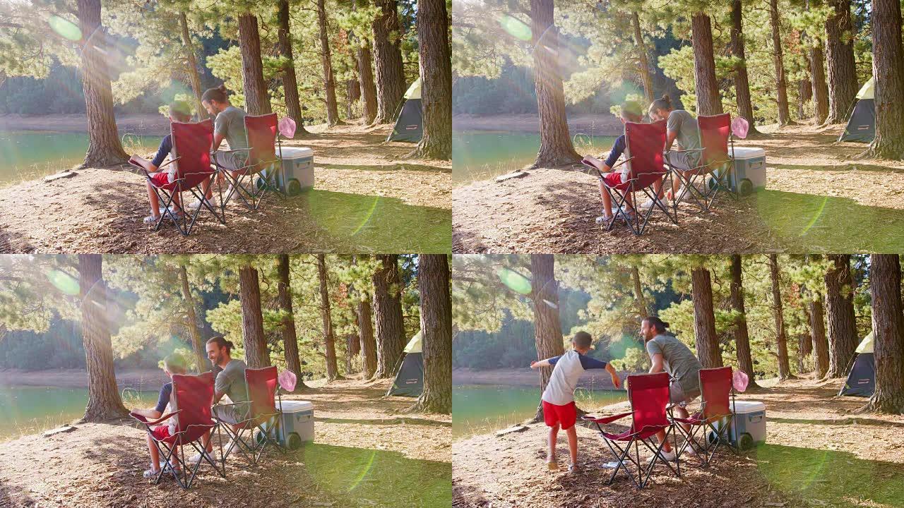 父子俩坐在湖边的露营椅上