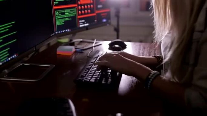 女人用手敲电脑代码，黑屋子里的电脑。工作中的黑客，程序员