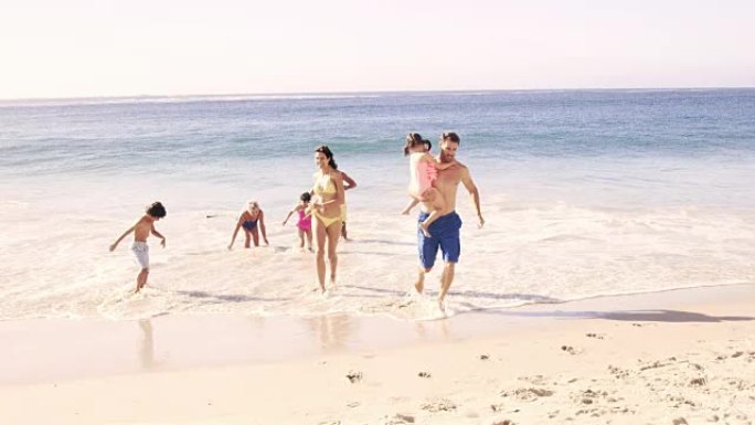 可爱的家庭在海滩上跑出水面