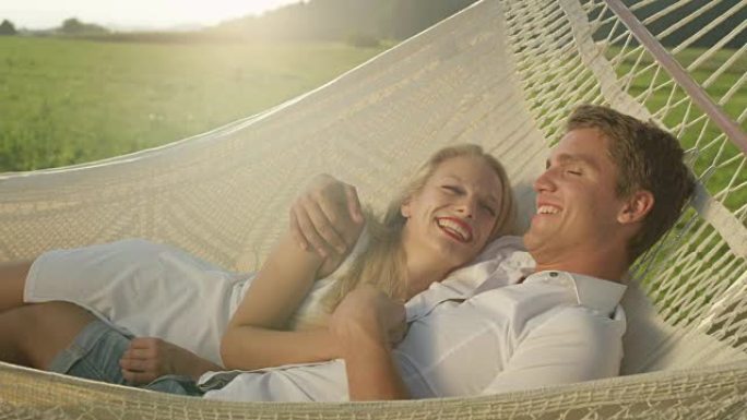 肖像: 快乐的男人躺在浪漫的吊带中亲吻额头上的女友