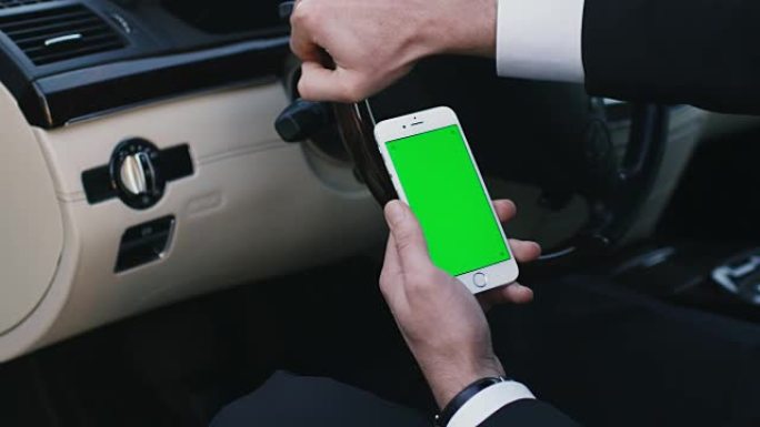 一个商人在汽车上使用带有模拟绿屏的智能手机的特写镜头。