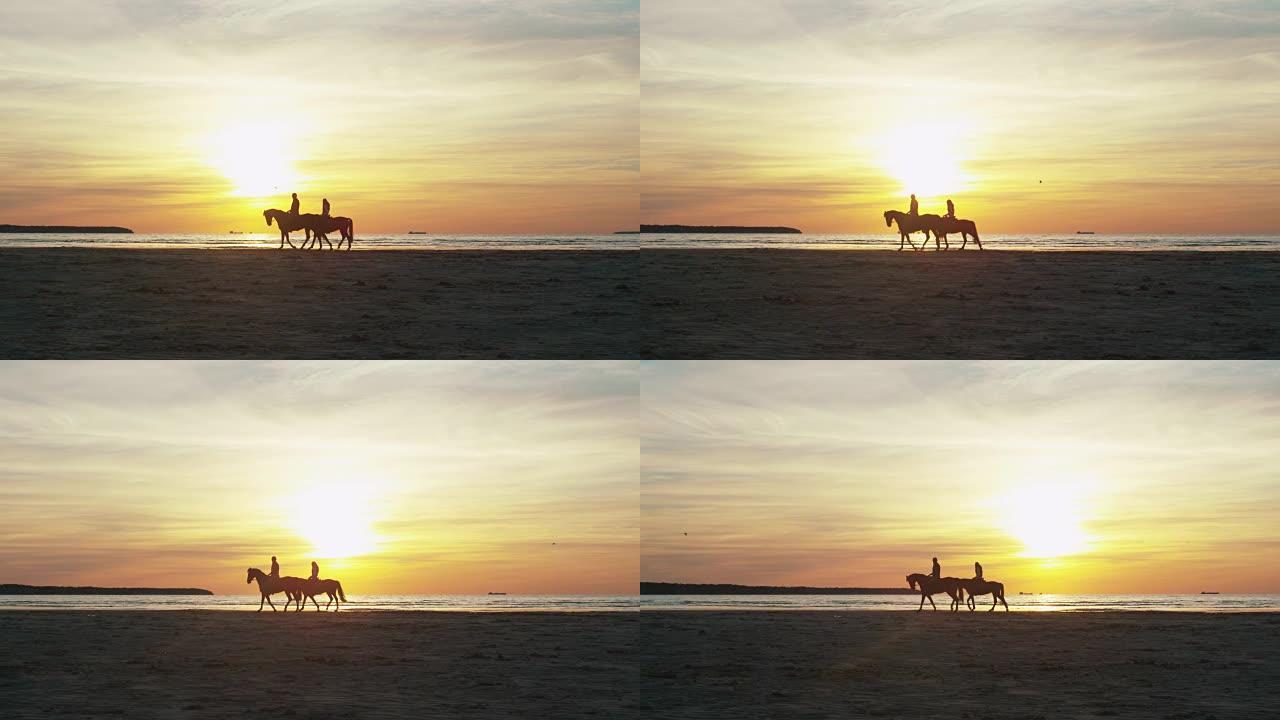 日落灯光下海滩上两个骑马的人的剪影。