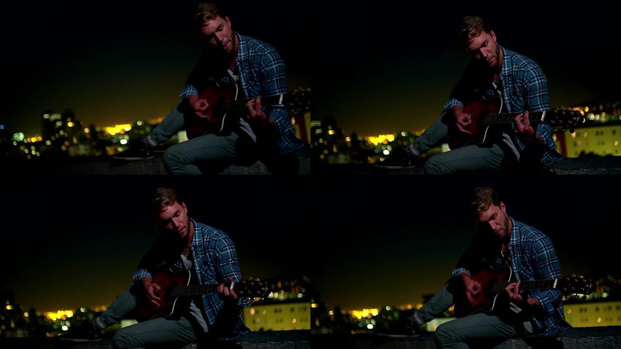 时髦的少年男孩晚上坐在屋顶上弹吉他