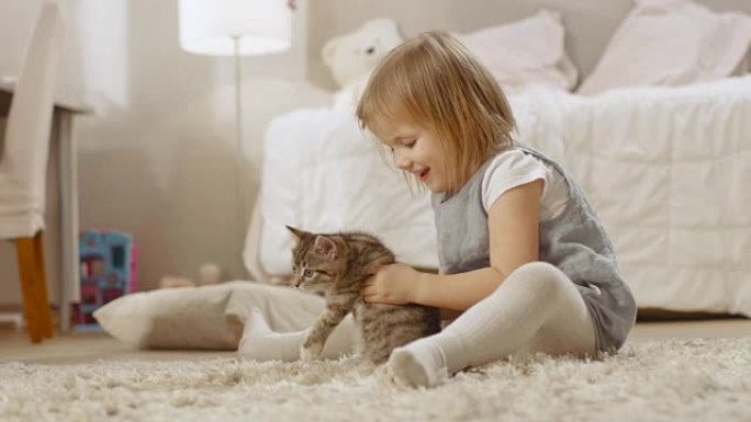 可爱的小女孩坐在地板上，快乐地抱着她最喜欢的条纹小猫。慢动作。
