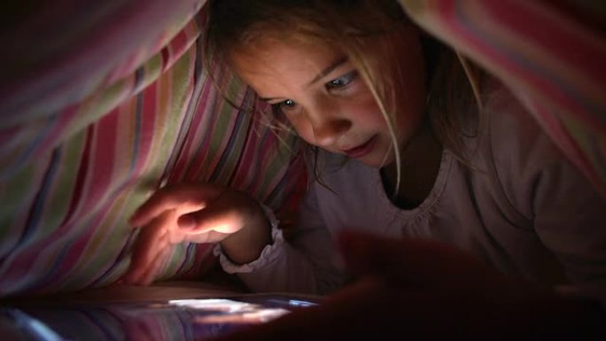 晚上在床罩下看数字平板电脑的女孩