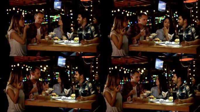在一家餐馆里快乐的夫妇一边聊天一边享用炸薯条和汉堡