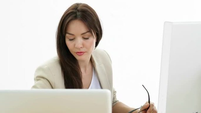 用笔记本电脑和电脑在办公桌前工作的女人