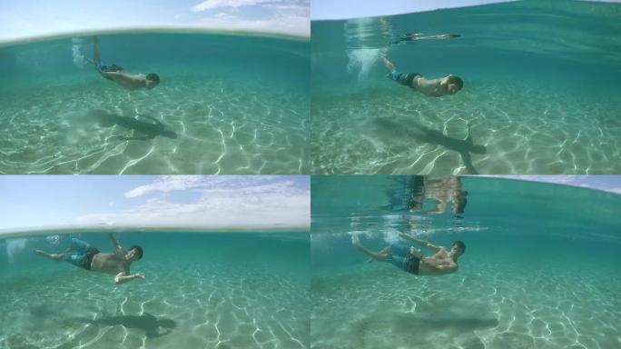 水下: 快乐的年轻人在令人惊叹的海底与沙质地板水下游泳