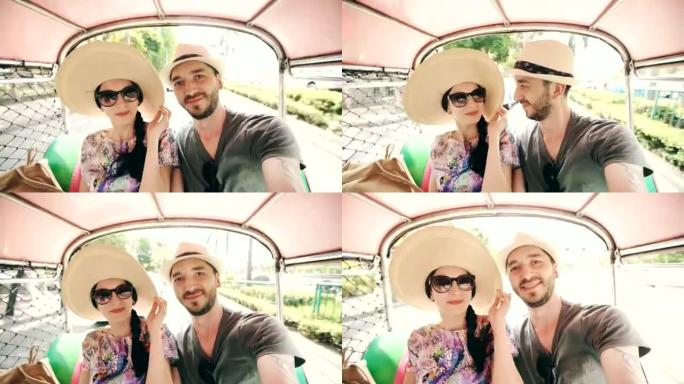 年轻英俊的男人和他的女朋友骑着传统的泰国巴士songteo在智能手机上自拍。夫妻在蜜月期间旅行泰国