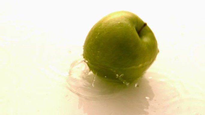 苹果在潮湿的白色表面上掉落并旋转