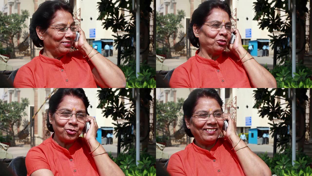 在户外打电话的印度老年妇女